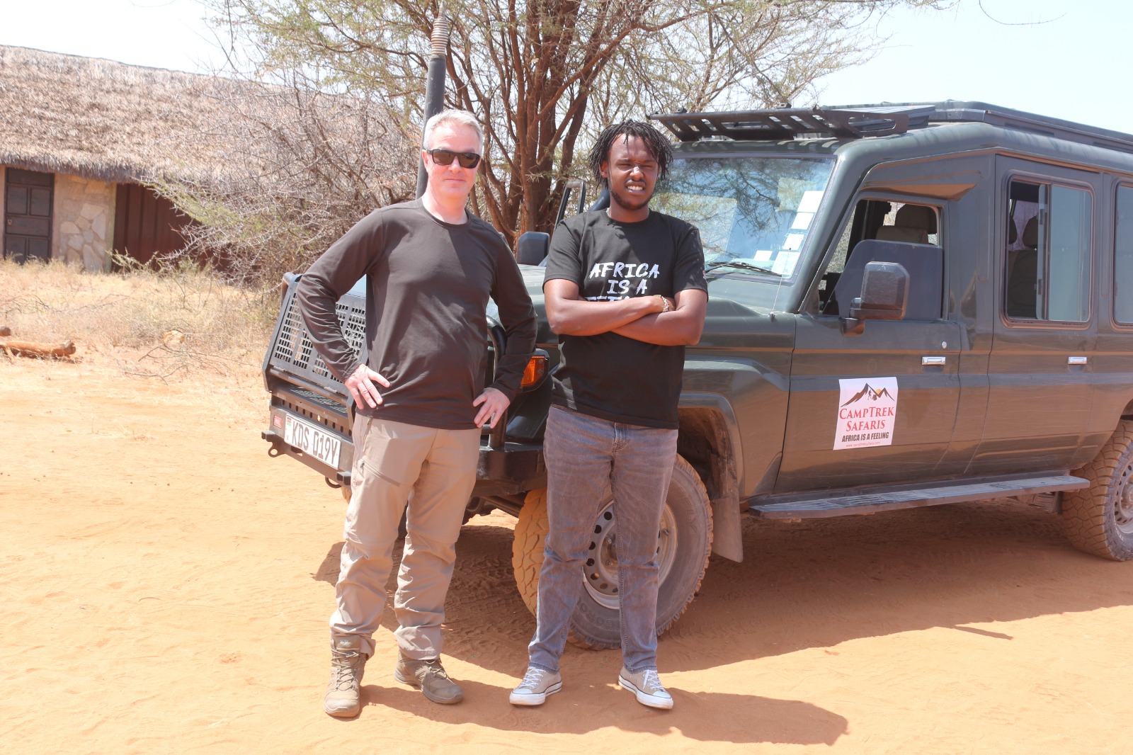 CampTrek Safaris guide with guest standing beside a 4x4 safari vehicle