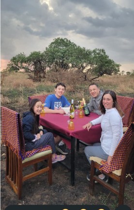 Family enjoying an outdoor bush dinner at sunset on safari
